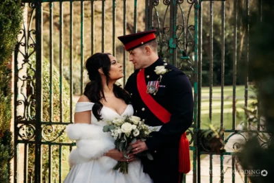 Military groom and bride at gate, wedding portrait.