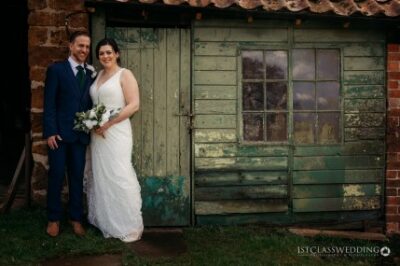 Bride and groom smiling by rustic green door.