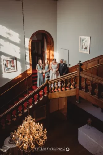 Wedding guests on grand staircase with chandelier.