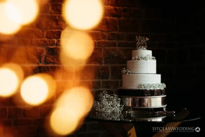 Elegant wedding cake with 'Mr & Mrs' topper, bokeh lights.