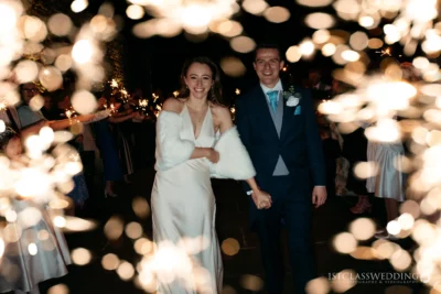 Couple smiling at sparkler-lit wedding celebration.
