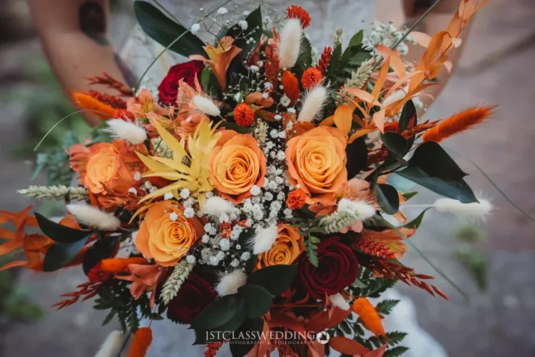 Autumnal wedding bouquet with orange and red roses.