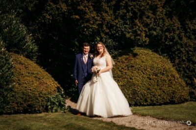 Bride and groom smiling in sunny garden setting.