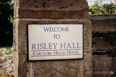 Risley Hall hotel welcome sign on stone pillar.