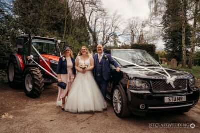 Bride, groom, and guest with cars on wedding day.