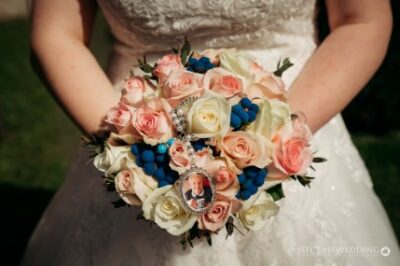 Bride holding bouquet with pink roses and blue accents.