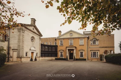 Elegant historic mansion with autumn foliage in England.