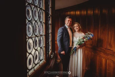 Bride and father smiling in vintage wood-panelled room.
