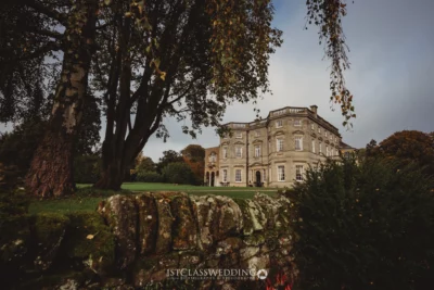Elegant historic mansion amidst lush gardens and stonework.