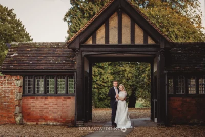 Couple posing under rustic archway at countryside wedding