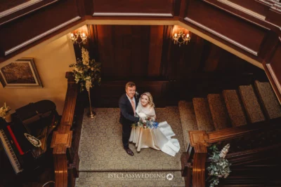 Wedding couple posing on elegant wooden staircase.