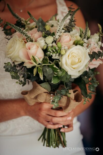 Bride holding elegant pink and white wedding bouquet.