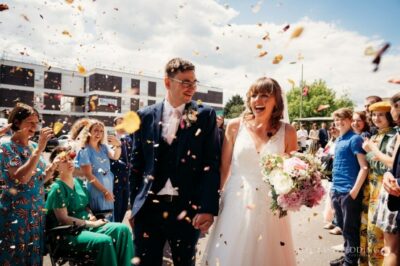 Bride and groom smiling with confetti thrown at wedding.