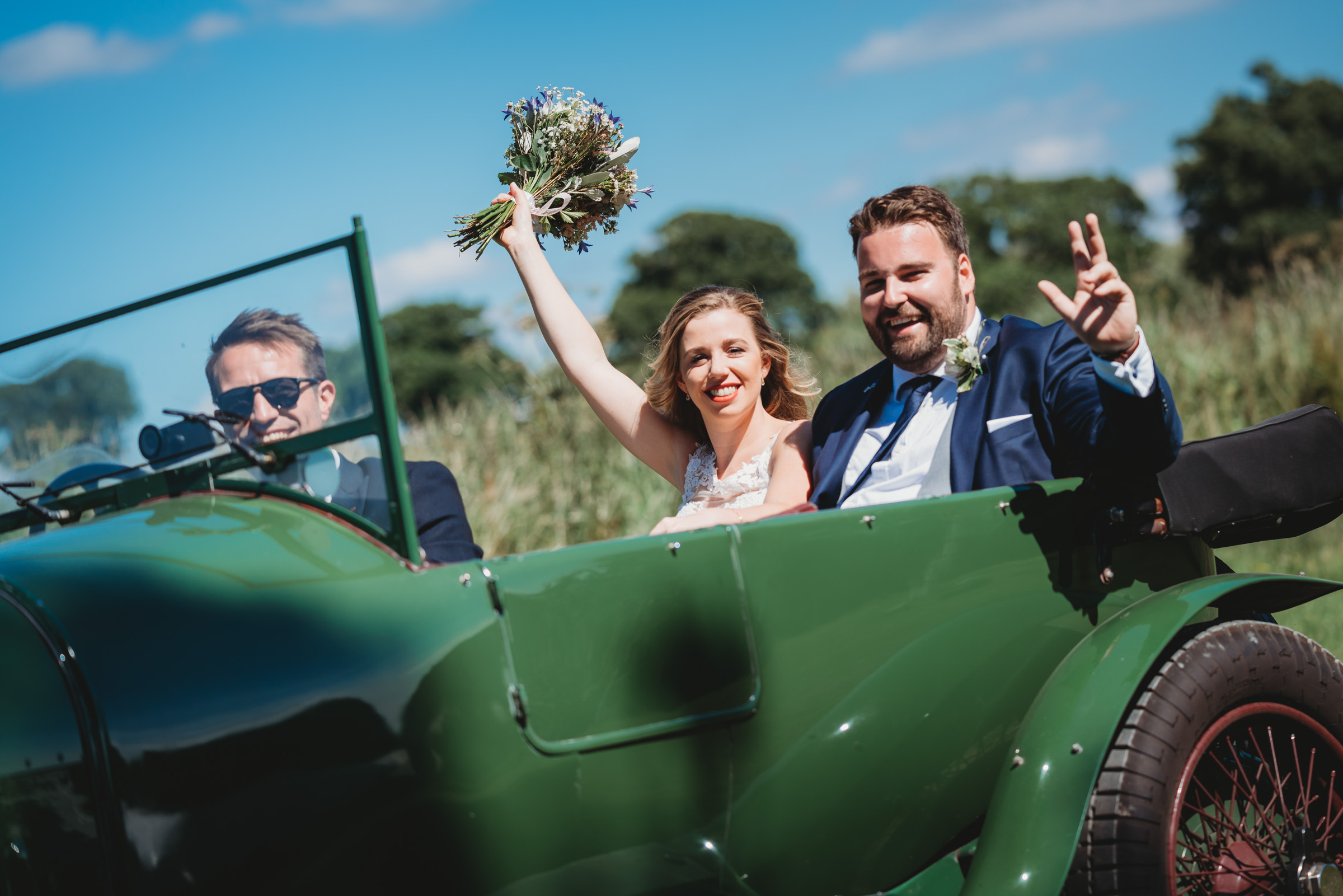 bride and groom celebrating in vintage car