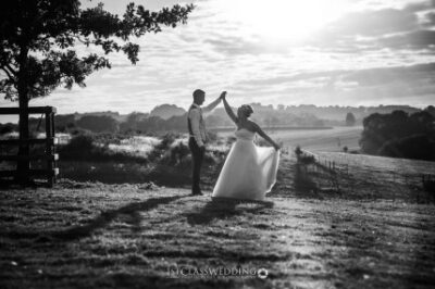 Bride and groom walking in countryside at sunset.