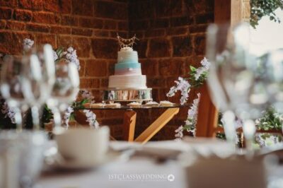 Wedding cake on table in rustic brick-walled venue.