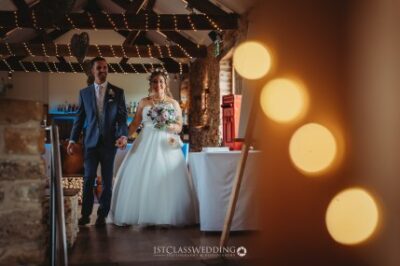 Wedding couple entering reception with bokeh lights.