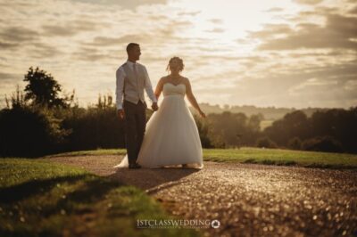 Couple walking at sunset, countryside wedding scene.