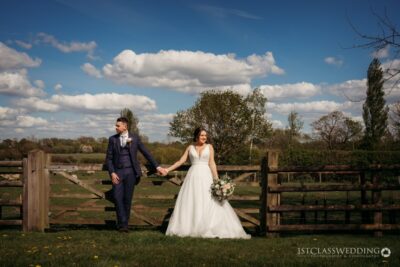 Wedding couple holding hands in countryside setting.