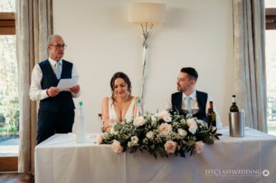 Wedding speech, happy couple listening, elegant floral decoration.