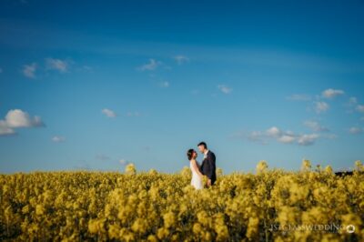 Couple posing in blooming yellow rapeseed field.