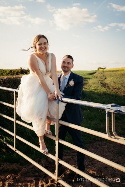 Bride and groom laughing in sunny countryside.