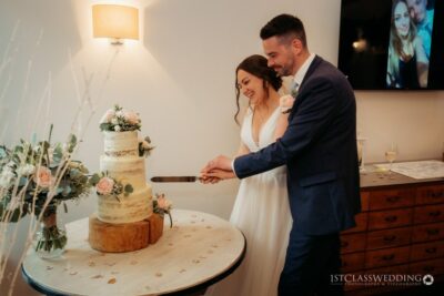 Couple cutting wedding cake together.