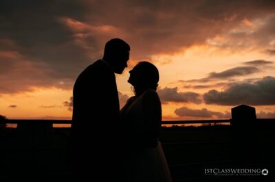 Couple silhouette against sunset sky.
