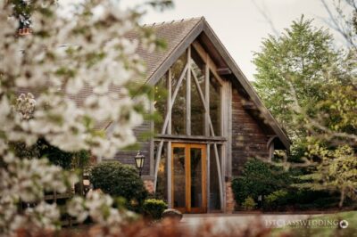 Timber-framed house entrance framed by white blossoms.