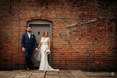 Bride and groom standing by vintage brick wall.