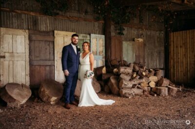 Couple posing in rustic barn with logs.