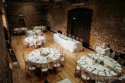 Elegant brick-walled wedding reception venue with round tables.
