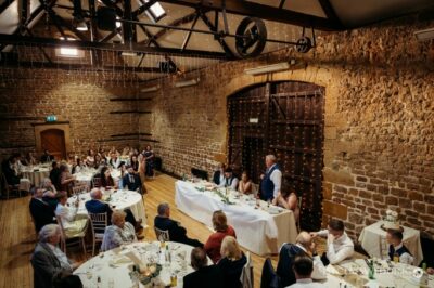 Wedding reception in rustic venue with guests and speeches.