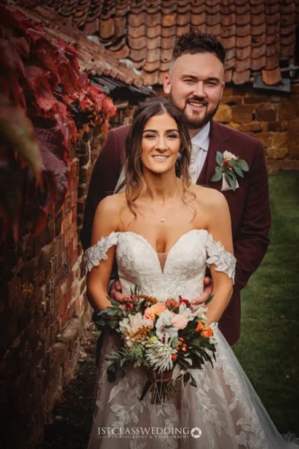 Bride and groom posing with autumnal bouquet.