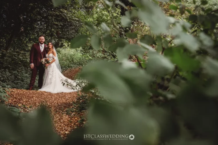 Couple posing in forest aisle, wedding day, nature background.
