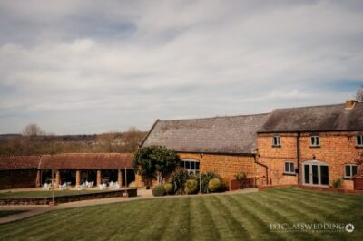 Rustic wedding venue with manicured lawn in countryside.