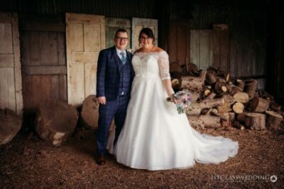 Couple in wedding attire posing in rustic woodshed.