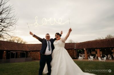 Bride and groom holding 'love' sign at wedding.