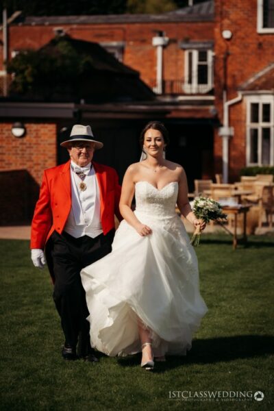 Bride walking with man in red coat outdoors.