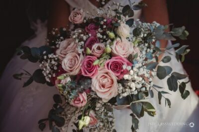 Bride holding bouquet with pink and white roses.