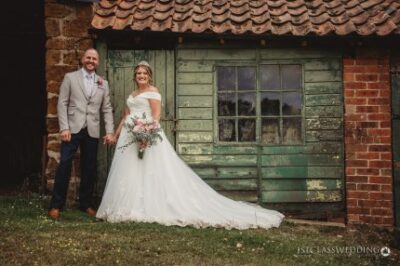 Bride and groom smiling by rustic building.