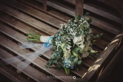 Bridal bouquet on wooden bench at wedding