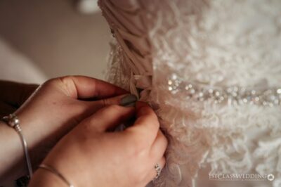 Hands fastening a bride's wedding dress detail
