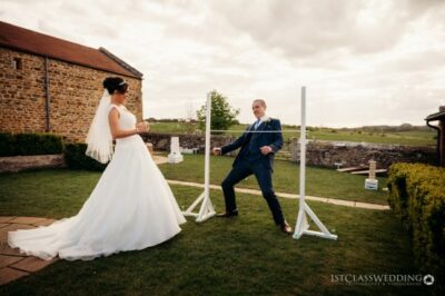Bride and groom playing limbo at outdoor wedding.