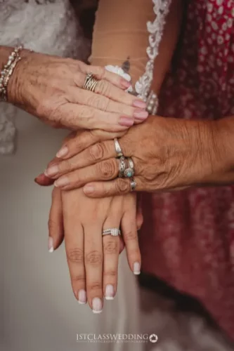 Three generations holding hands, showcasing wedding rings.