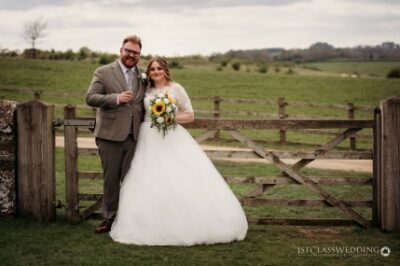 Bride and groom smiling in countryside wedding scene.