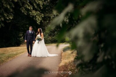 Bride and groom walking on park path after wedding.