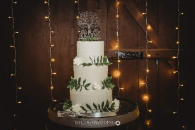 Elegant wedding cake with greenery and fairy lights.