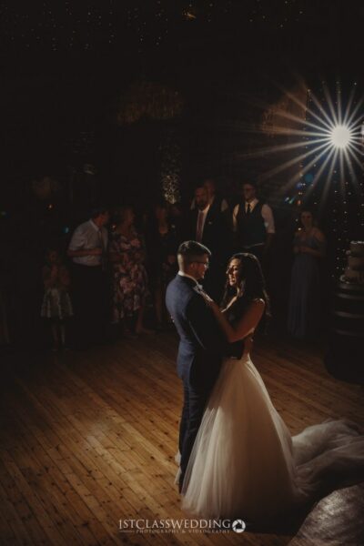 Bride and groom first dance under spotlight at wedding.