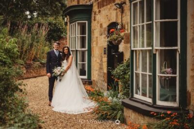 Bride and groom posing by historic stone building